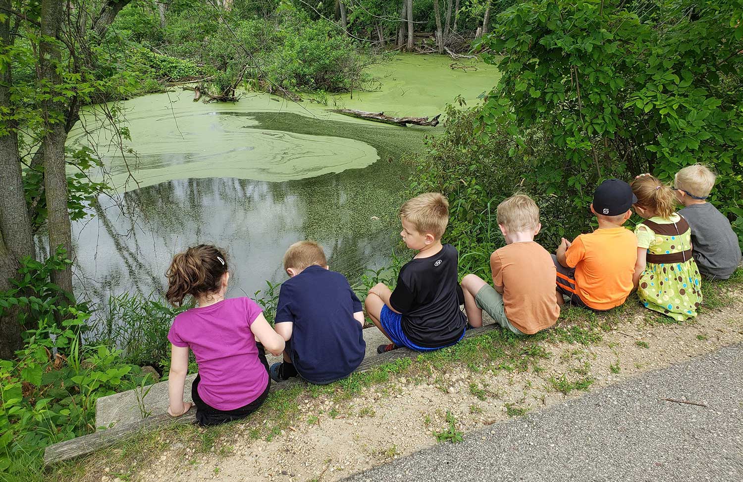 kids sitting near pond