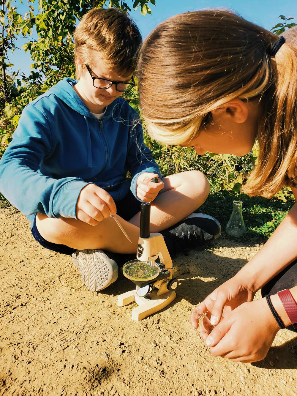 camp kids using microscope out in nature