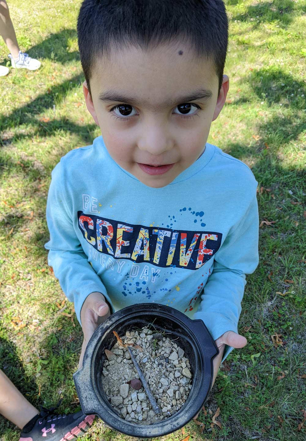 young camper collecting items from nature into a bowl
