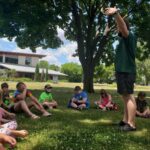 camp kids learning outside under a tree
