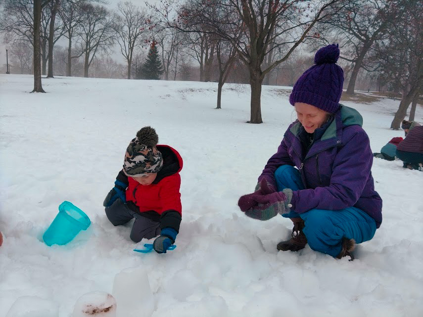 Chelsea Bruemmer, Environmental Educator, playing in the snow with a child.