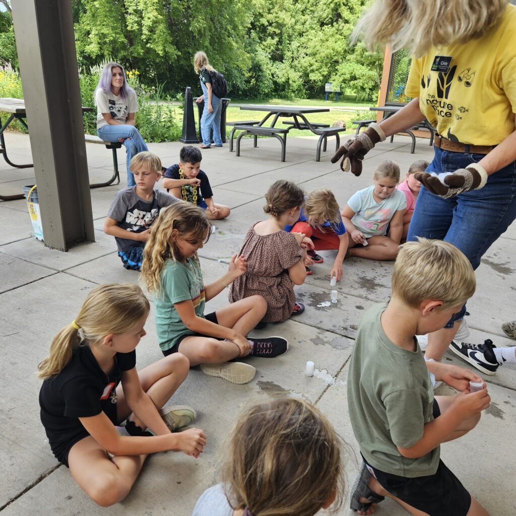 Summer day campers and AmeriCorps Environmental Educators conducting experiments on the patio.