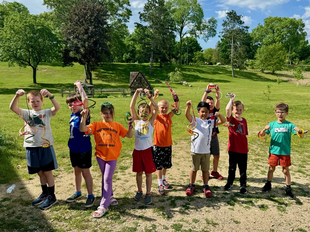 Kids holding up rubber snakes as part of a snake-themed birthday party.